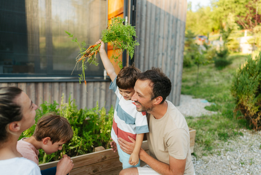 Jeunes enfants qui récoltent avec leurs parents les légumes de leur propre potager.