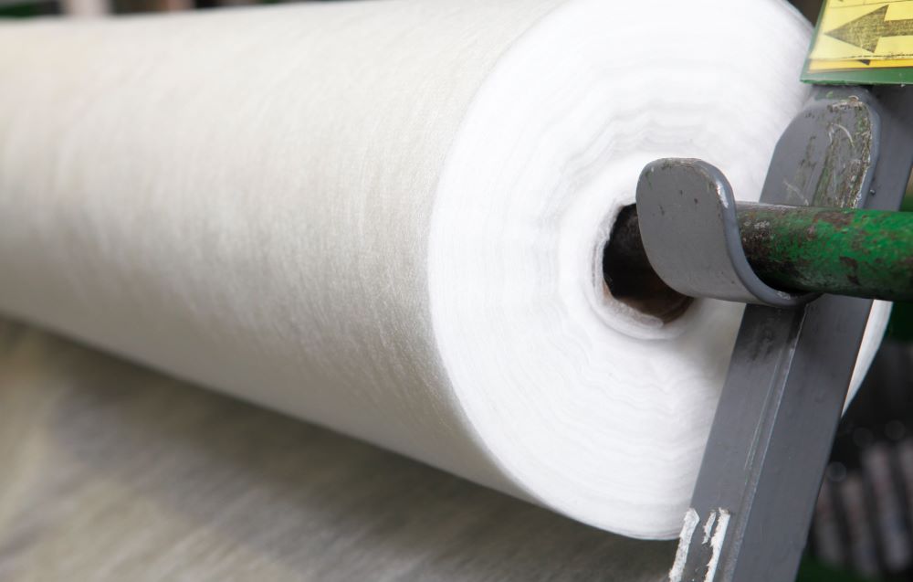 Rouleau de géotextile blanc non tissé, prêt à être déroulé pour des travaux d’aménagement paysager ou de jardinage.