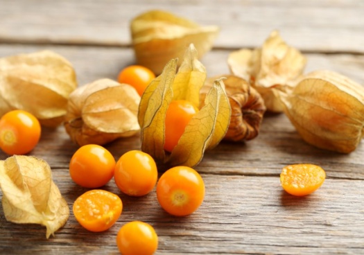 Photo de plusieurs physalis déposés sur une surface en bois.
