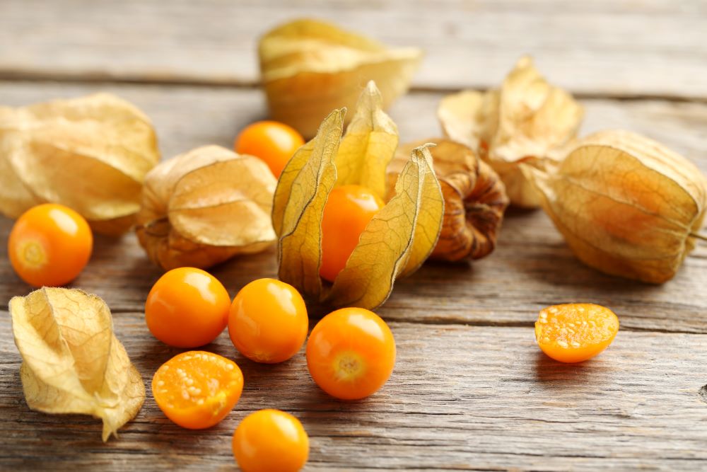 Photo de plusieurs physalis déposés sur une surface en bois.