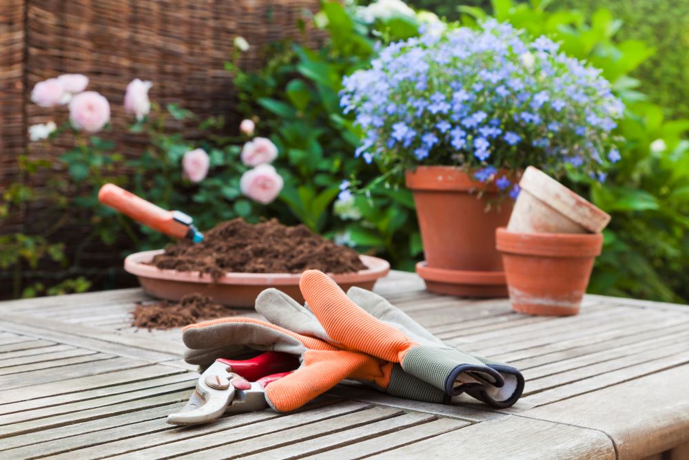 Paire de gants de jardinage posée sur une table de jardin en bois.