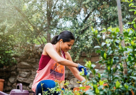 Photo montrant une jeune femme dans son jardin en train de jardiner.