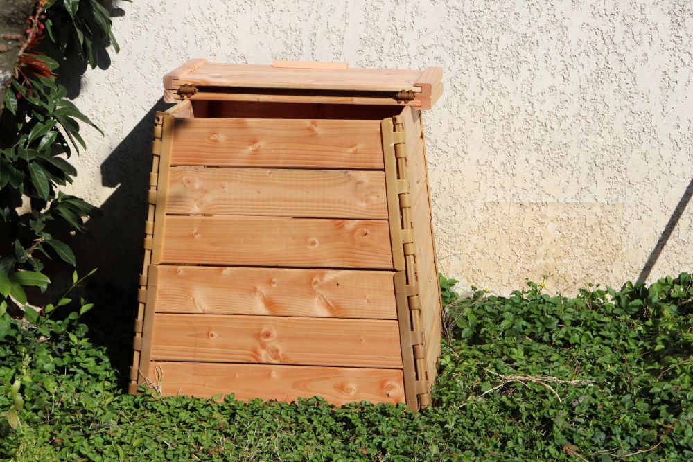 Photo d'un composteur en bois posé sur l'herbe dans un jardin.